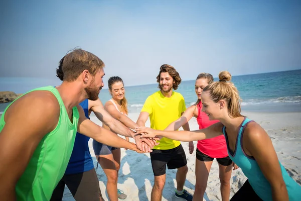 Vänner som står med staplade händer på stranden — Stockfoto