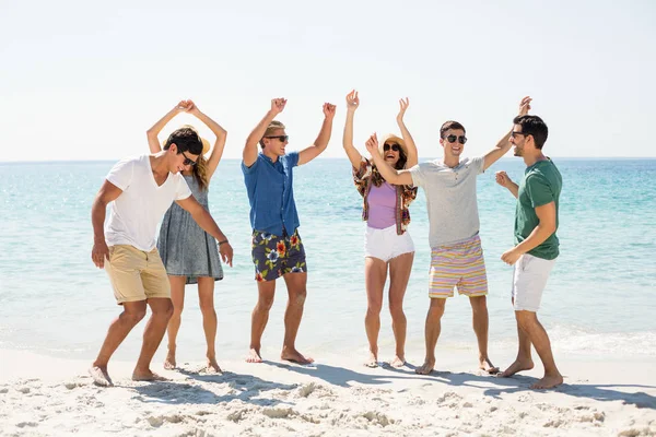 Vänner dansa på stranden på solig dag — Stockfoto
