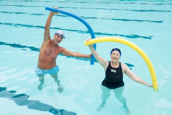 Pareja mayor haciendo ejercicio con fideos de piscina —  Fotos de Stock