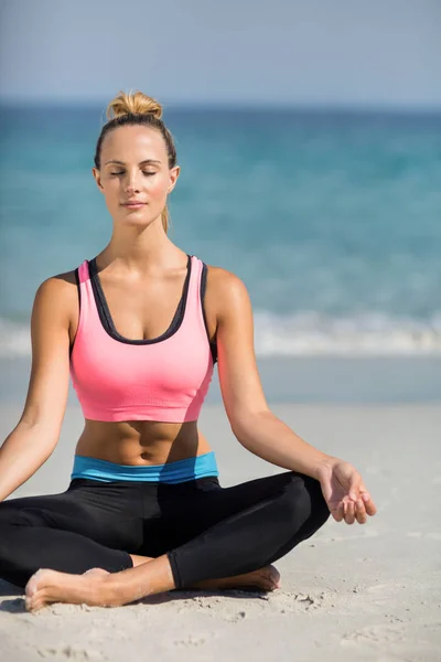 Женщина медитирует в позе лотоса на пляже — стоковое фото