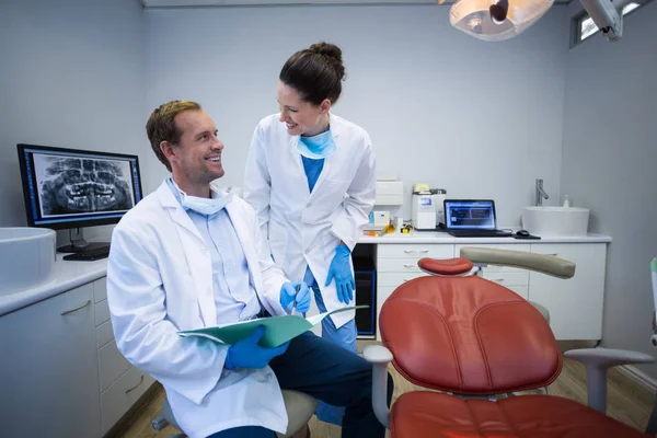 Dentists discussing on medical report in clinic — Stock Photo, Image
