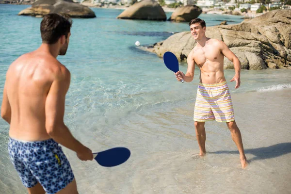 Amigos varones jugando matkot en la orilla en la playa —  Fotos de Stock