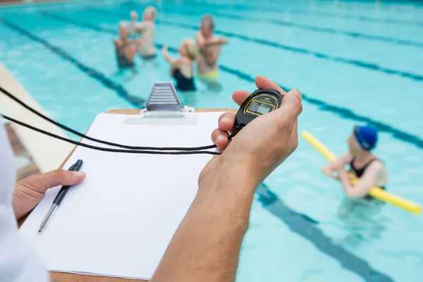 Treinador de natação olhando para cronômetro perto da piscina — Fotografia de Stock