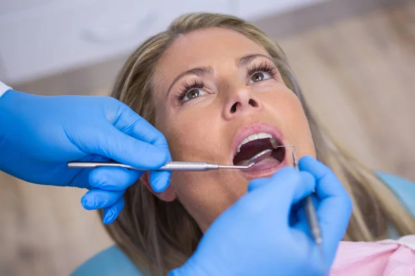 Dentista examinando uma paciente feminina com ferramentas — Fotografia de Stock