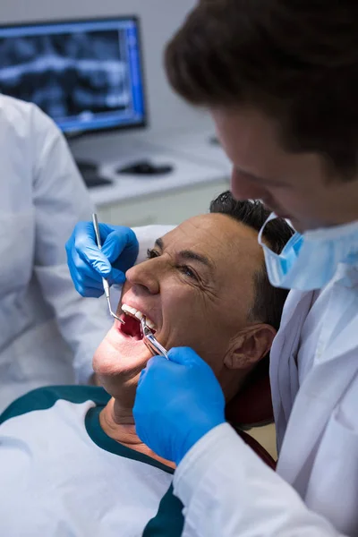 Zubaři zkoumání mužského pacienta s nástroji — Stock fotografie