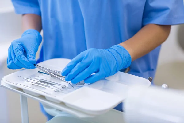 Enfermera recogiendo herramientas dentales de bandeja —  Fotos de Stock