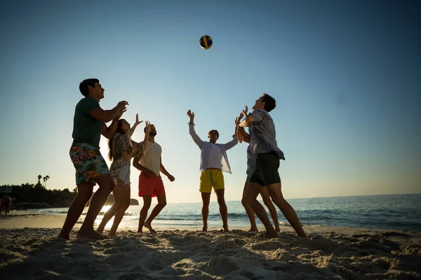 Друзья играют в волейбол на берегу на пляже — стоковое фото
