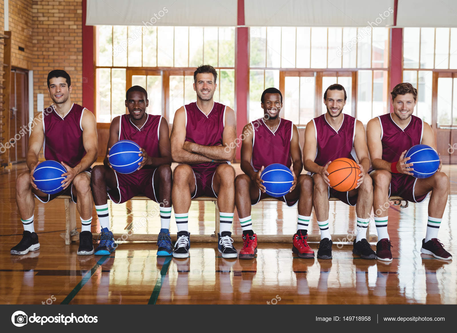 Basketball players on bench with basketball Stock Photo by