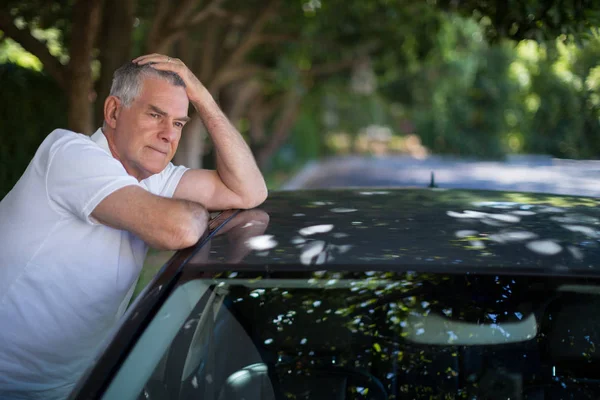 Tensed senior man leaning on car — Stock Photo, Image