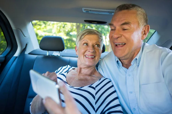 Старшая пара, использующая мобильный телефон в машине — стоковое фото