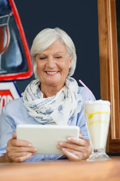 Mosolyogva tablet tartó magas rangú női — Stock Fotó