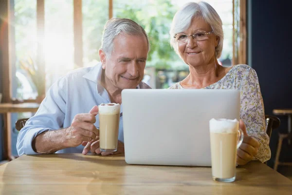Senior couple using laptop while having coffee — Stock Photo, Image
