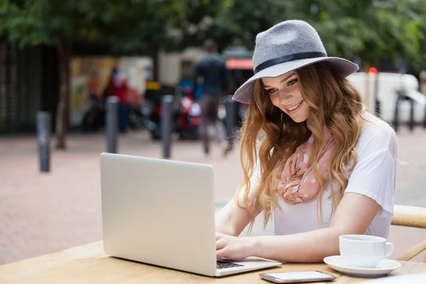 디지털 노트북을 사용 하 여 테이블에 모자를 착용 해 여자 — 스톡 사진