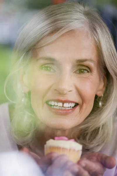 Smiling woman holding cupcake — Stock Photo, Image