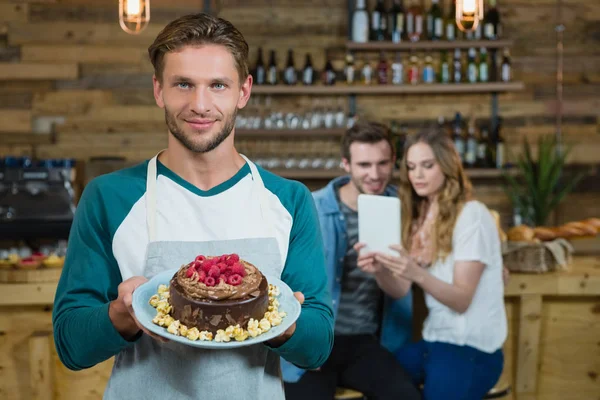 Camarero sosteniendo plato de pastel y cliente — Foto de Stock