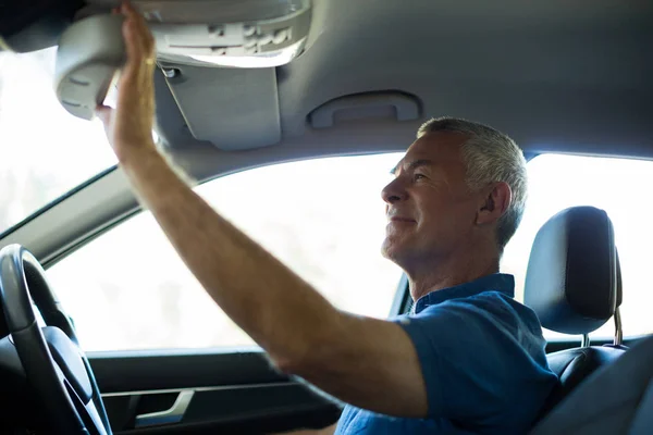 Hombre mayor ajustando espejo retrovisor en coche —  Fotos de Stock