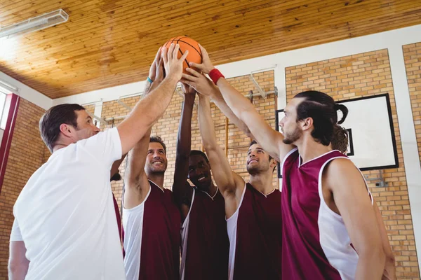 Jogadores e treinador segurando basquete juntos — Fotografia de Stock