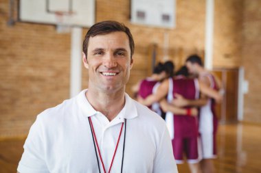 Confident coach standing in basketball court clipart