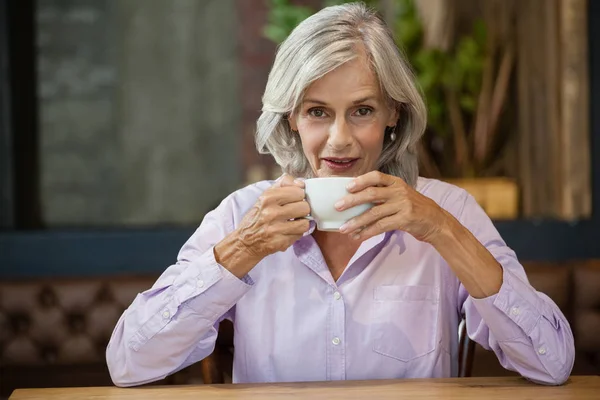 Senior Kvinna med kaffekopp sitter vid bord — Stockfoto