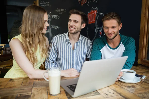 Friends using laptop while sitting at table — Stock Photo, Image