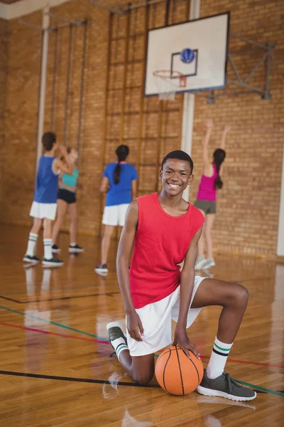 Bir basketbol ile diz çökmüş okullu çocuk — Stok fotoğraf