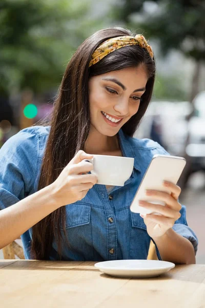 Kobieta przy użyciu telefonu podczas picia kawy — Zdjęcie stockowe