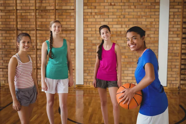 Улыбающиеся школьники, стоящие с баскетболом — стоковое фото