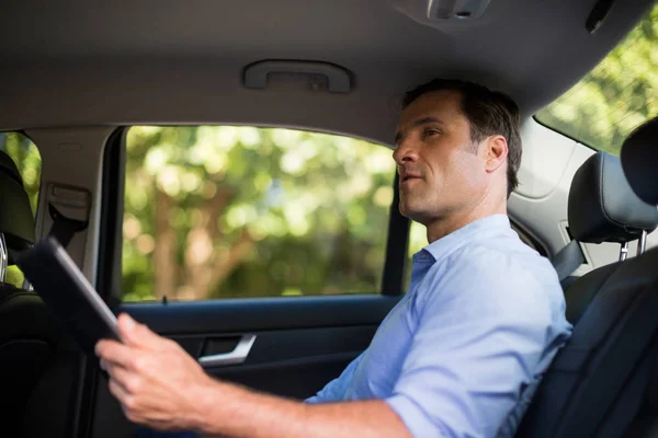 Homem segurando tablet digital no carro — Fotografia de Stock