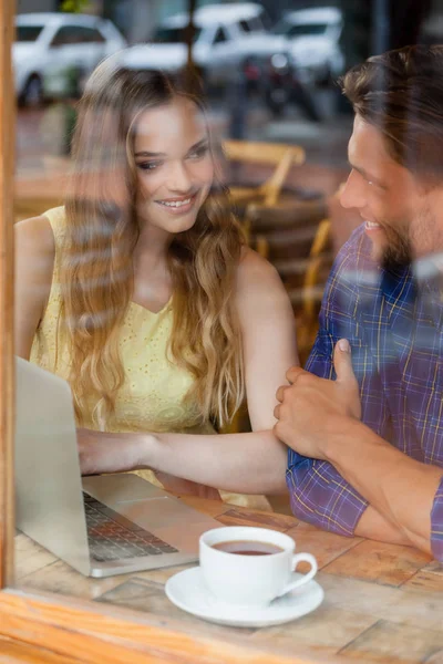 Casal usando laptop digital enquanto sentado no café — Fotografia de Stock