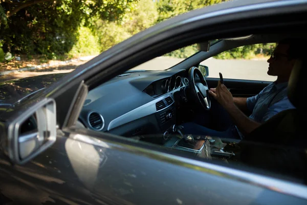 Человек, использующий телефон за рулем автомобиля — стоковое фото