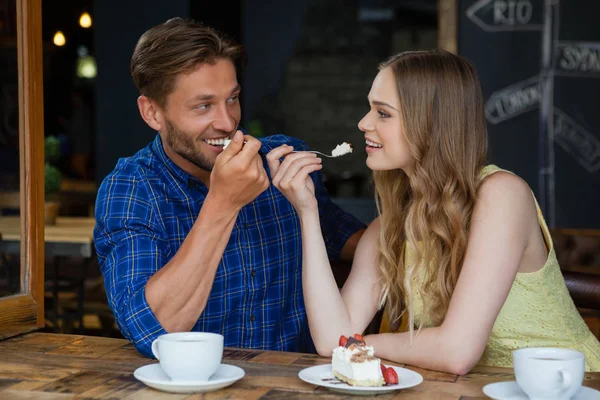 Пара ест сладкую пищу, сидя за столом — стоковое фото
