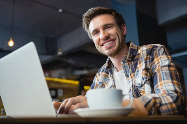 Ung man använder laptop med kopp kaffe — Stockfoto