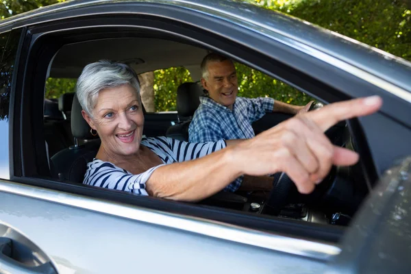 Senior mulher apontando para longe no carro — Fotografia de Stock