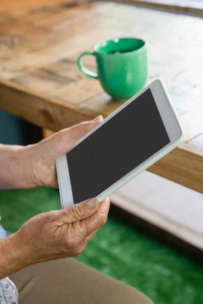 Mulher sênior segurando tablet enquanto bebe café — Fotografia de Stock