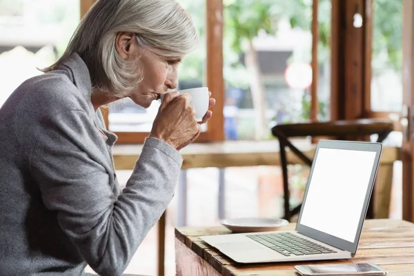 Starší žena pije kávu — Stock fotografie