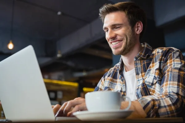 Homem usando laptop enquanto toma café — Fotografia de Stock