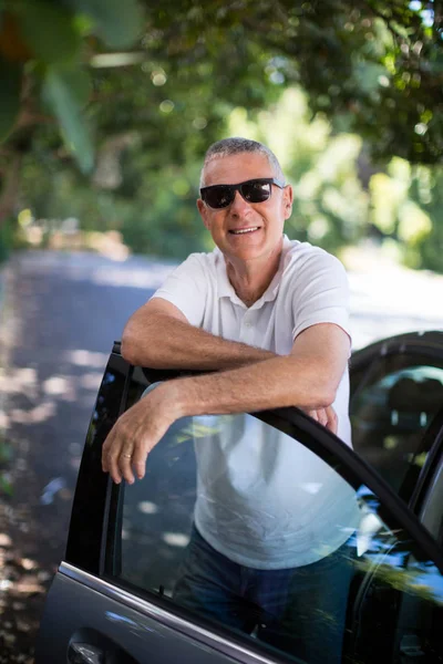 Sonriente hombre apoyado en la puerta del coche —  Fotos de Stock