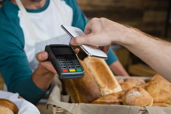 Customer paying bill through smartphone — Stock Photo, Image