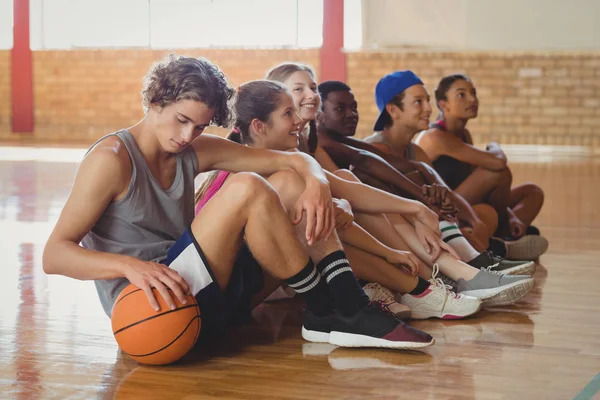 Kinderen zitten op de vloer in basketbalveld — Stockfoto