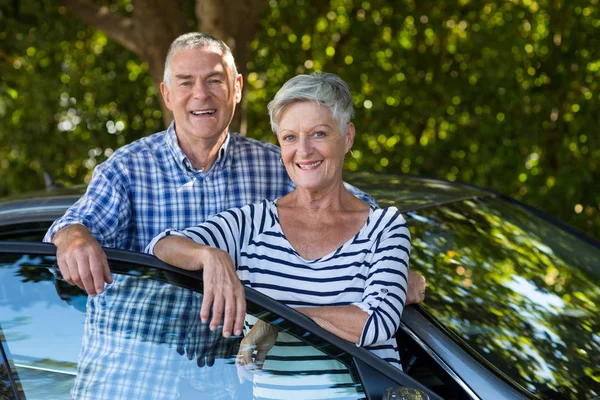 Starší pár, opírající se o dveře auta — Stock fotografie