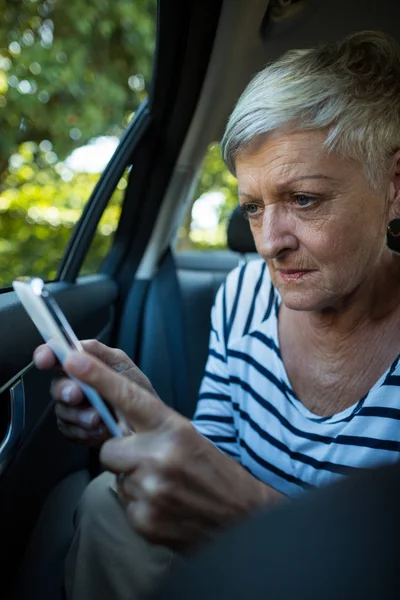 Mujer mayor usando el teléfono móvil en el coche — Foto de Stock