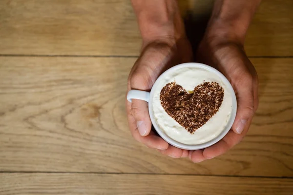 Persona sosteniendo taza de café con arte espumoso — Foto de Stock