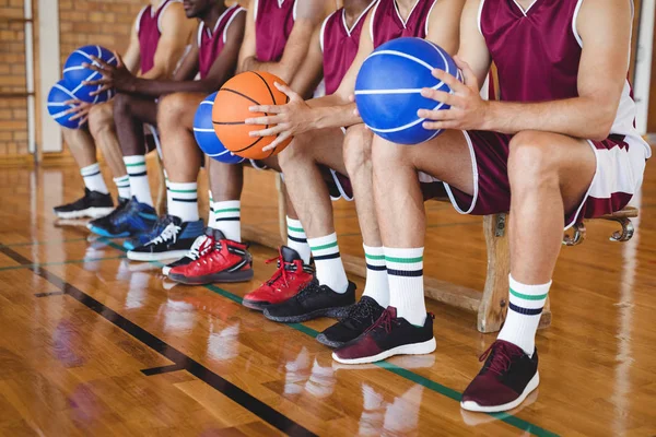 Jugadores de baloncesto sentados en el banco con baloncesto —  Fotos de Stock
