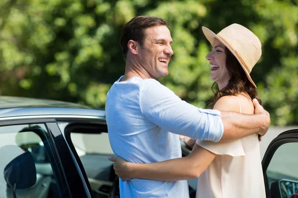 Paar omarmen met de auto op zonnige dag — Stockfoto