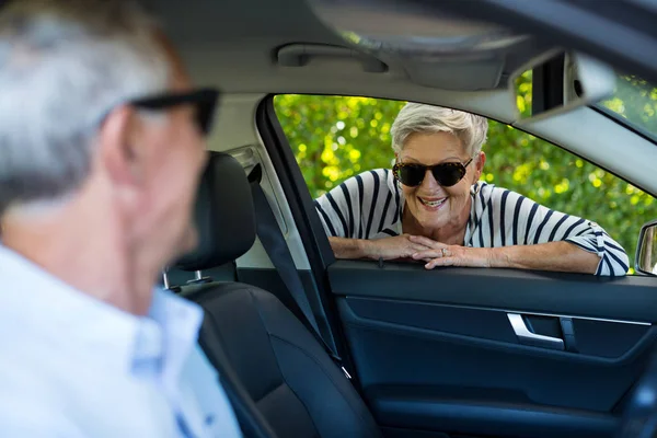 Старшая женщина смотрит на мужчину сидящего в машине — стоковое фото