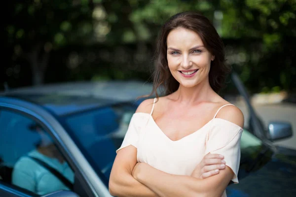 Улыбающаяся женщина стоит рядом с машиной — стоковое фото