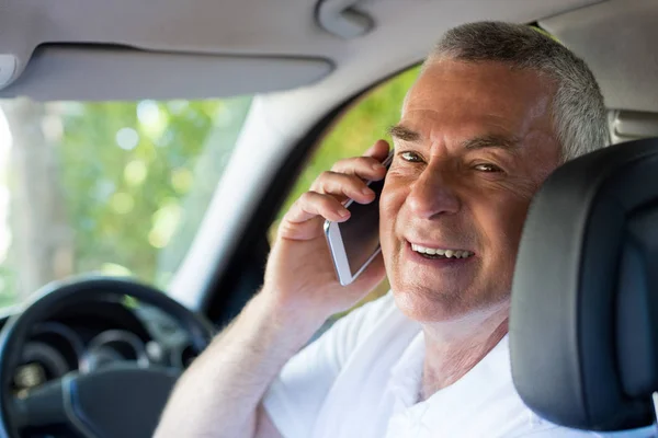 Smiling senior man talking on phone in car — Stock Photo, Image