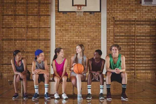 Schüler sitzen auf einer Bank im Basketballfeld — Stockfoto