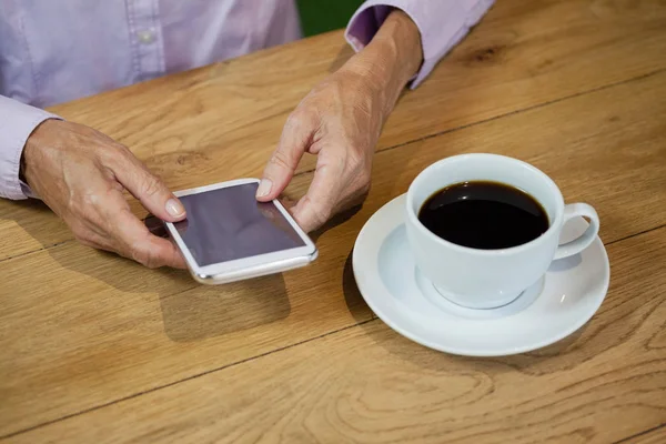 年配の女性がカフェでスマート フォンを使用して — ストック写真