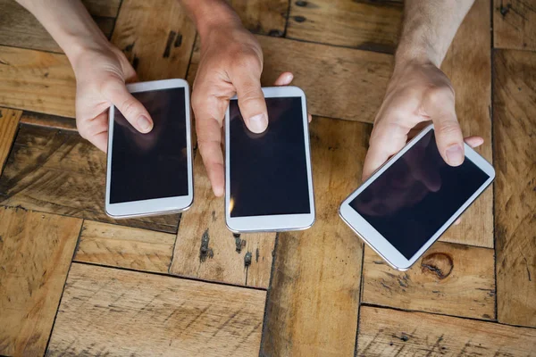 Amigos sosteniendo el teléfono móvil en la mesa — Foto de Stock